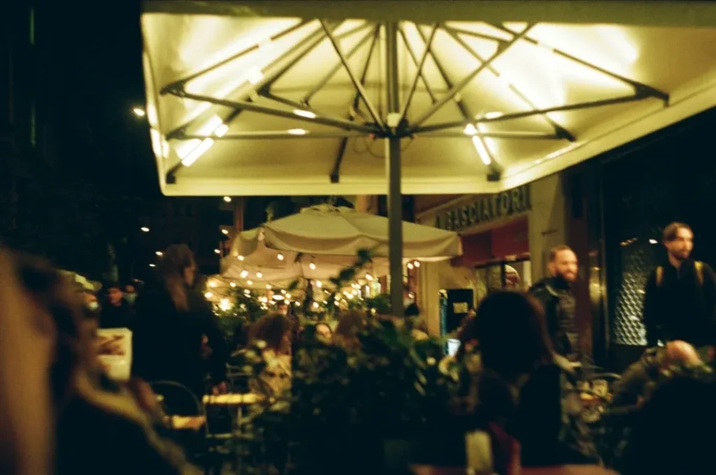 a group of people sitting at tables under an umbrella